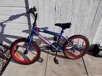 Full side view of a blue and red children's bicycle with visible brand and model on frame.