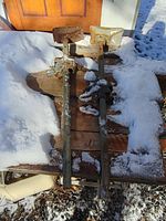Two old rusted car jacks set on snow-covered wooden board