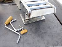 Photo of Roscan Deluxe pasta machine with detachable crank and clamp on a surface.