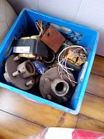 Blue tote containing two trailer wheel hubs, several electrical parts with wiring.