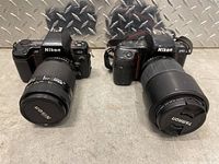 Both Nikon cameras shown next to each other on floor with metal diamond plate background.