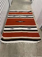 Large rectangular Southwestern style carpet on concrete floor, showing full length and pattern.