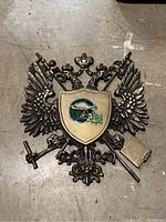 Full view of metal wall sign showing double-headed eagle with shield crest containing football helmet graphic.