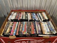 Box filled with various DVD movies, showing a broad collection of different genres and titles.