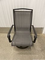 Front view of gray mesh sling patio chair with metal armrests and swivel base