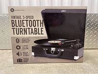 Box of the vintage 3-speed Bluetooth turntable shows branding, speed options 33 1/3, 45, 78 RPM, built-in speakers, suitcase design, wireless Bluetooth connectivity.