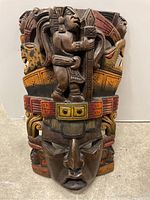 Front view of the hand-carved wooden tribal mask showing detailed carvings and colorful paint.