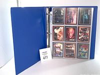 Blue three-ring binder open to display 9 Star Trek trading cards in plastic sleeves showing front artwork with characters and starships.