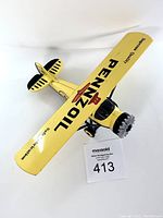 Top-front angled view showing yellow wing with "PENNZOIL" and "Supreme Quality" branding, radial engine nose, and landing gear.