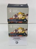 Two stacked boxes of Yellow Mountain Imports 60 Marble Set, Petal Style with 6 colors, each marble 14 mm diameter.