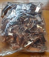 Bag containing numerous gold-colored metal clips with hooks, shown in transparent plastic packaging.