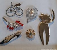 Top view of all 6 pins and brooches together, showing designs and scale.