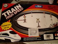 Box shows image of circular high-speed train track with train and accessory signaling pieces included