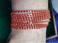 Red rhinestone bracelet worn on wrist displaying sparkle and red color.