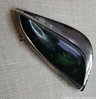 Close-up front view of silver pin with green stone inset, showing polished stone and curved shape.