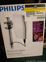 Front side of product box showing Philips logo and product photo with features including compact design, weatherproof, noise reduction, and mounting options.