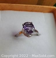 Front view of a sterling silver ring with a purple amethyst gemstone displayed in a white cushioned gift box.