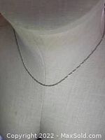 Silver necklace displayed on mannequin bust showing chain and length