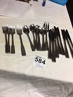 Photo showing the full partial flatware set laid out on a table, including knives, forks, and spoons.