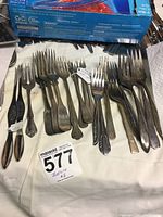 Various miscellaneous forks in mixed metal finishes placed on a cloth surface, showing tarnish and wear.
