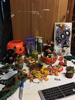 Wide view of all Halloween decorations on table including pumpkin bucket, fabric cat, wooden pumpkins, candle, porcelain house, BOO sign, fall leaves, and ghost placemats