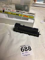 Black HO gauge model train engine with yellow stripe and Baltimore and Ohio lettering, displayed next to its original Atlas box.
