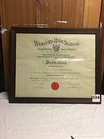 Oblique front view of the framed diploma showing text details, frame, and attached label 594