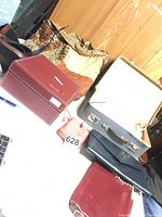 Photo showing purses and bags including red, tan, and black hard-sided and soft-sided purses.
