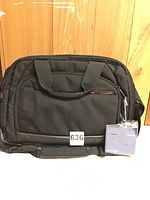 Front view of the black Samsonite laptop travel bag with handles and attached lock and key in packaging.