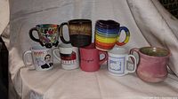 Front view of all 8 coffee mugs arranged in two rows showing their colors and styles