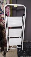 Closed view of the folded metal step ladder showing its three rectangular steps stacked vertically.