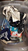 Top view of the lot showing the black Reebok sneakers, vintage shorts, books and other miscellaneous items inside a plastic tub.