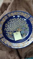 Photo of front side of Moroccan cobalt blue charger plate with gold peacock and floral design