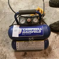 Top view of the Campbell Hausfeld air compressor showing brand label and pressure gauges, foam handle grip for portability.