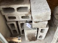 Photo showing stacked rectangular hollow cement blocks and a few solid concrete blocks.