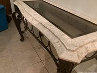 Side angle showing marble top with glass inset and metal detailing on the table base and legs.