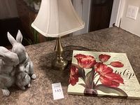 Photo showing the brass table lamp, tulip picture, and resin rabbit statue on a countertop.