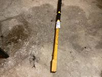 Top-down image of the manual wood splitter on a concrete floor showing the yellow shaft and wooden wedge head
