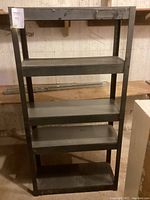 Full view of black metal shelving unit with five shelves, showing open construction and solid shelves.