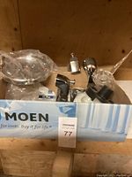 Overview photo of assorted new plumbing parts including Moen faucet components and other fixtures in original packaging.