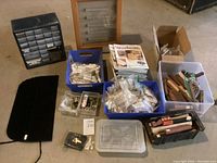 Overview of bins containing wood blanks, hardware kits, magazines, glue, display case and book