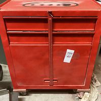 Front view of locked red metal rolling tool chest, closed drawers and door.