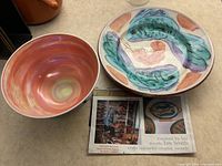 Two art pottery bowls by Jim Smith alongside a newspaper clipping showing Jim Smith at work, emphasizing the colorful painted fish and shrimp design on the larger bowl and warm swirls on the smaller bowl.