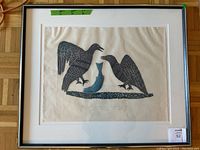 Framed stonecut print under glass with white mat, two black birds and a blue fish, green tape showing dimensions