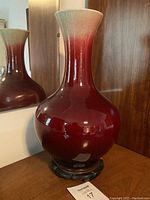 Full profile of oxblood red porcelain vase on wooden stand
