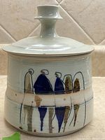 Front view of lidded jar showing shape and painted abstract figures