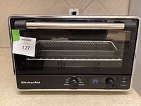 Front view of KitchenAid air fryer toaster oven showing control panel and glass door with handle.