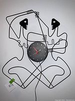 Overall front view of the clock showing full wire abstract figurative design and clock face