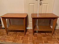 Two matching mid-century modern wood end tables side by side on parquet floor