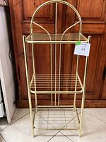 Front view of the retro 3 tiered brass shelf showing wire grid shelves and rounded arch back.